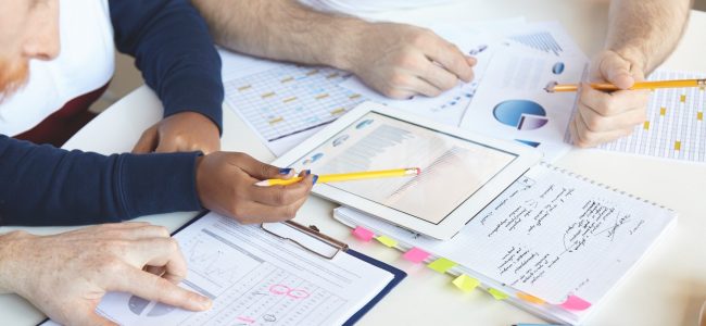 creative-people-diverse-ethnicities-working-business-plan-together-analyzing-growth-rate-value-goods-services-studying-market-counting-loss-using-touch-pad-pc-making-notes (1)