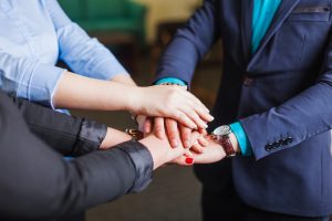 people-standing-office-holding-hands-together (1)